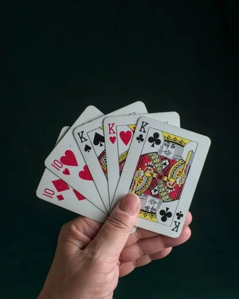 Hand holding a fan of playing cards with three kings